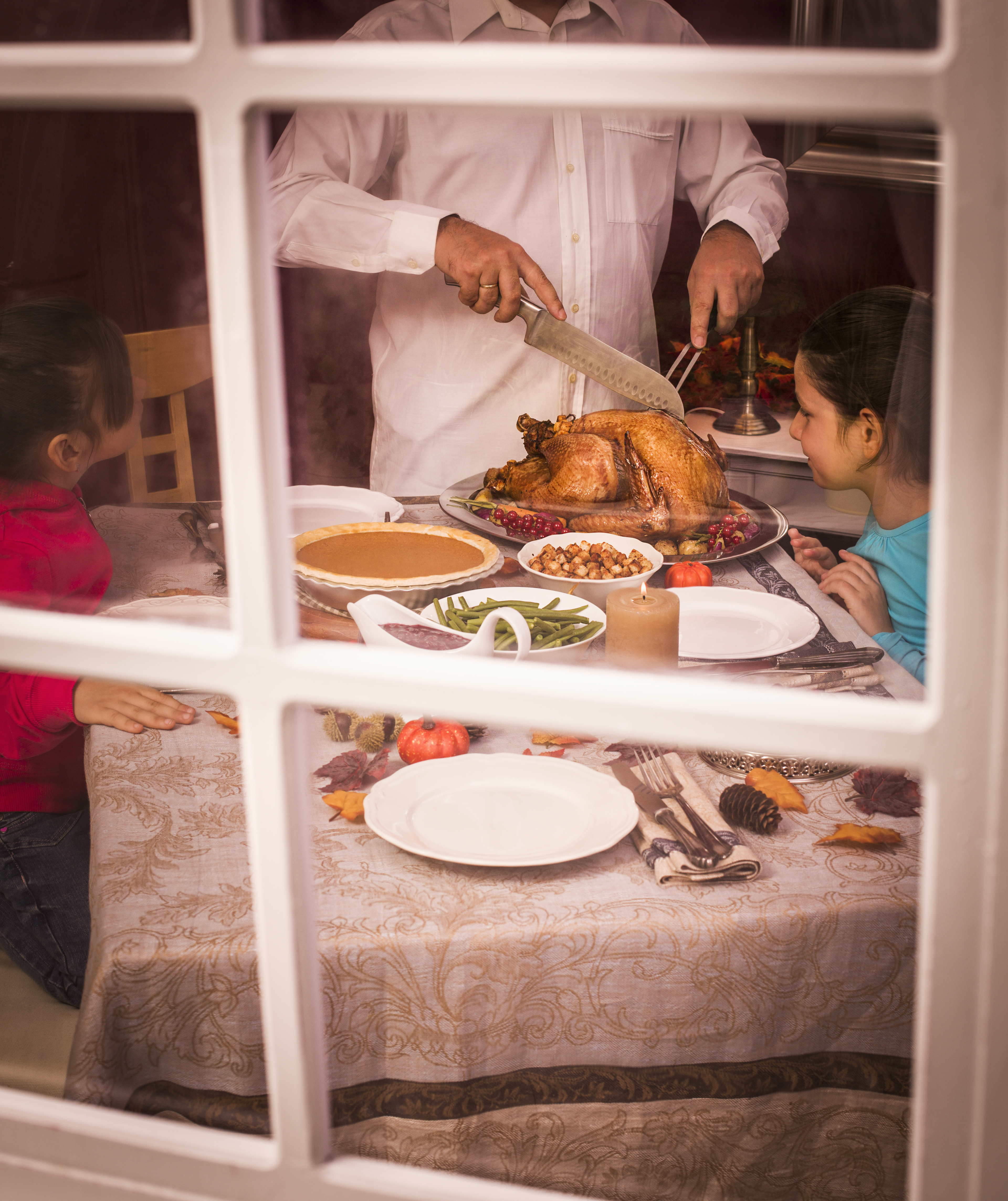 Young father carving thanksgiving turkey for his family