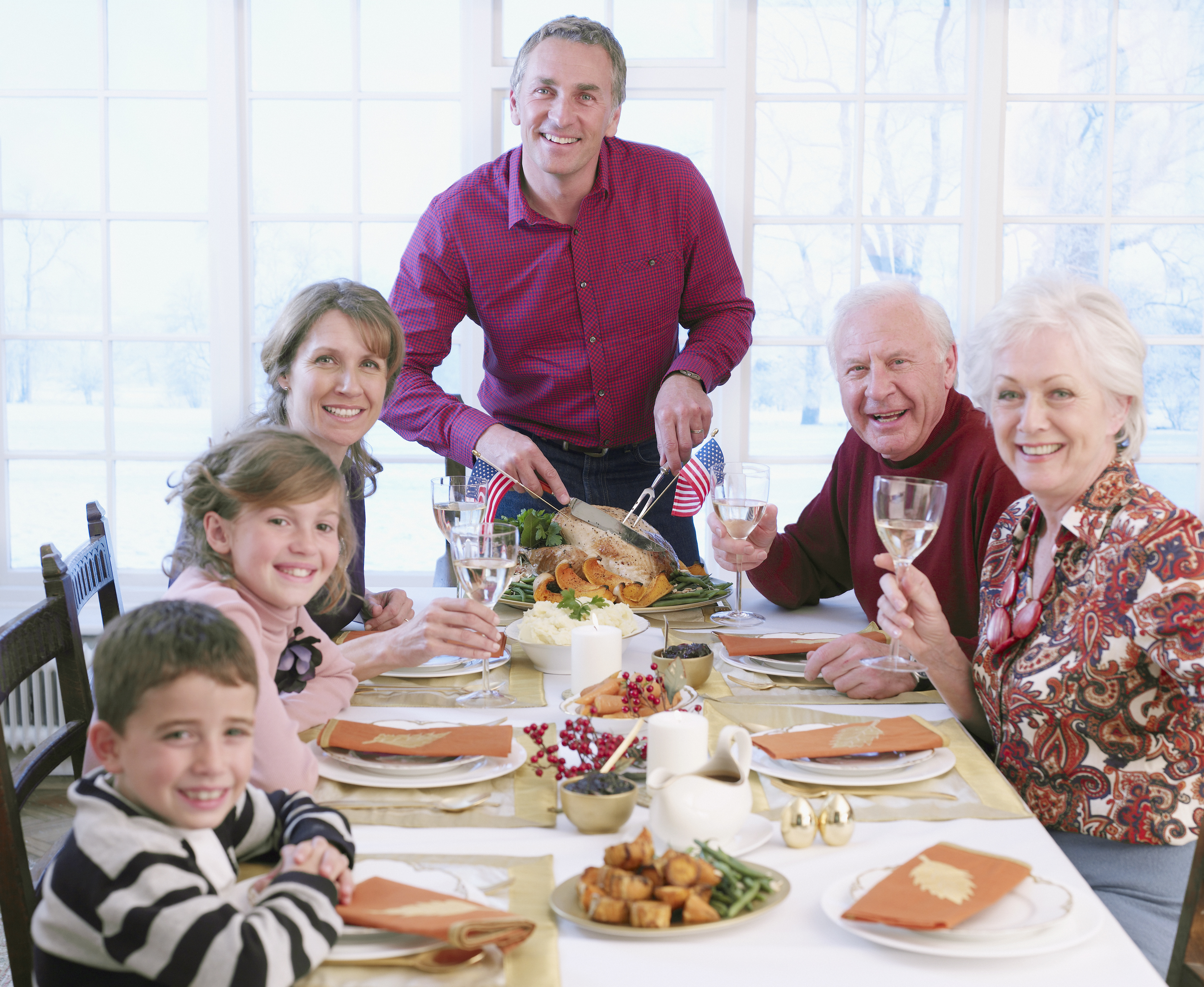 Man carving turkey for multi-generation family at table