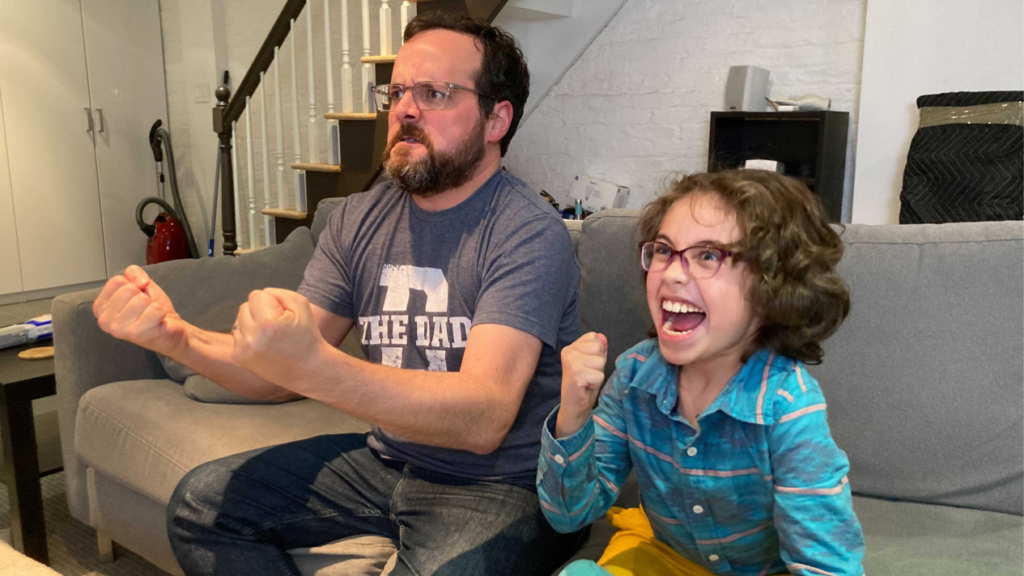 a man and his son cheer in excitement while playing a video game.