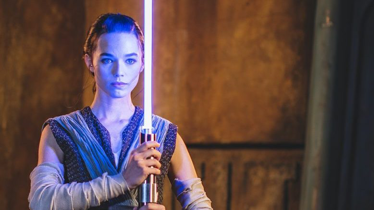 Rey holding a new Disney lightsaber